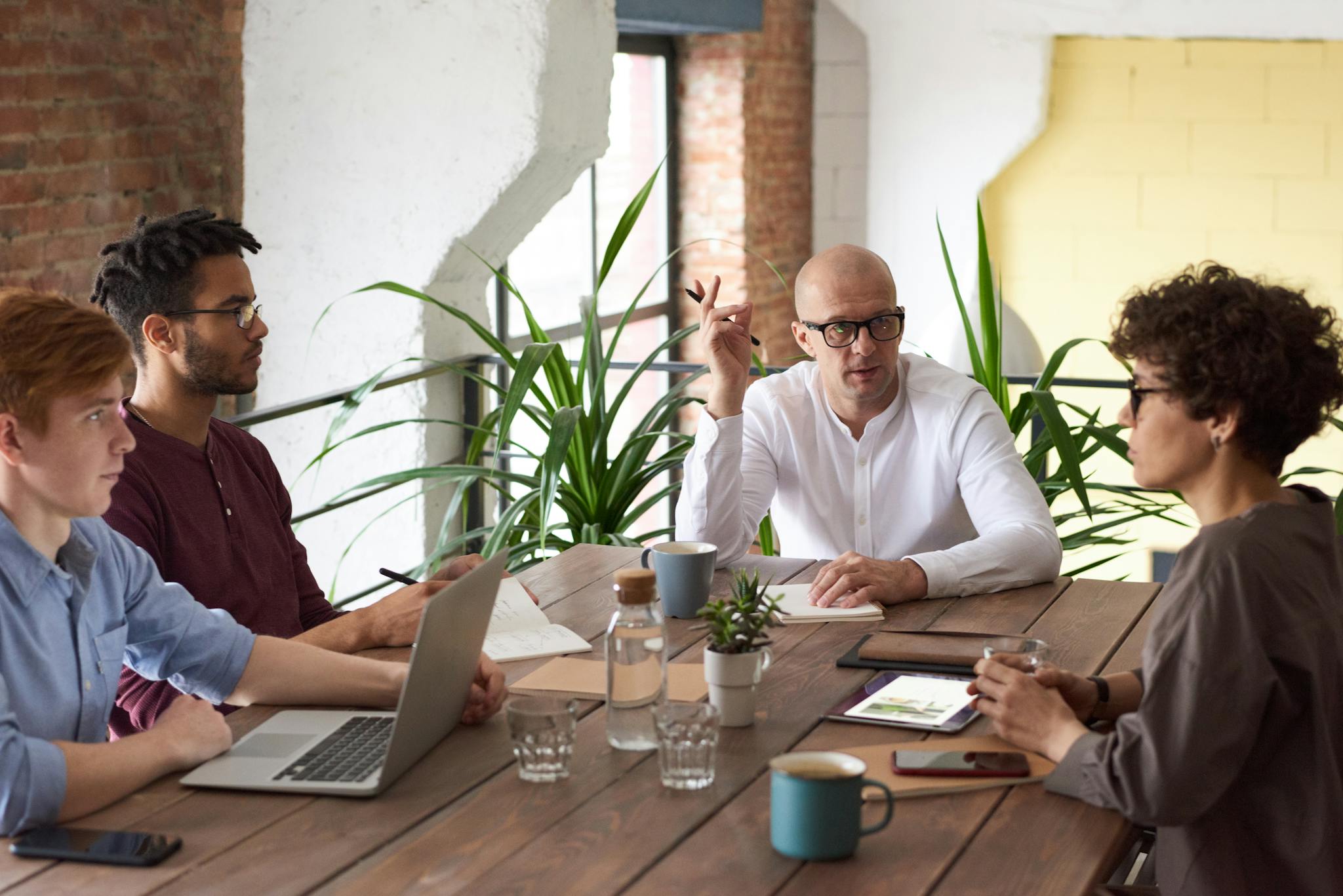 A group of colleagues in a modern office having a strategic discussion around a wooden table.